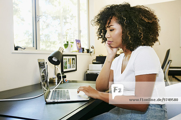 Mixed race woman using laptop at desk