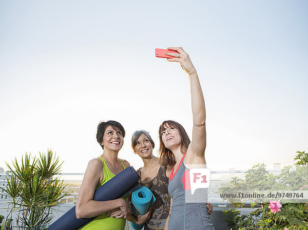 Women taking cell phone selfie on urban rooftop