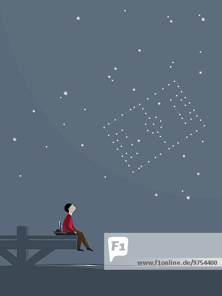 Junge sitzt auf einem Steg bei Nacht und sieht ein Fußballfeld am Himmel