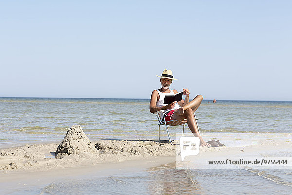 Mature man reading book on beach