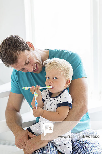 Father and son brushing teeth together