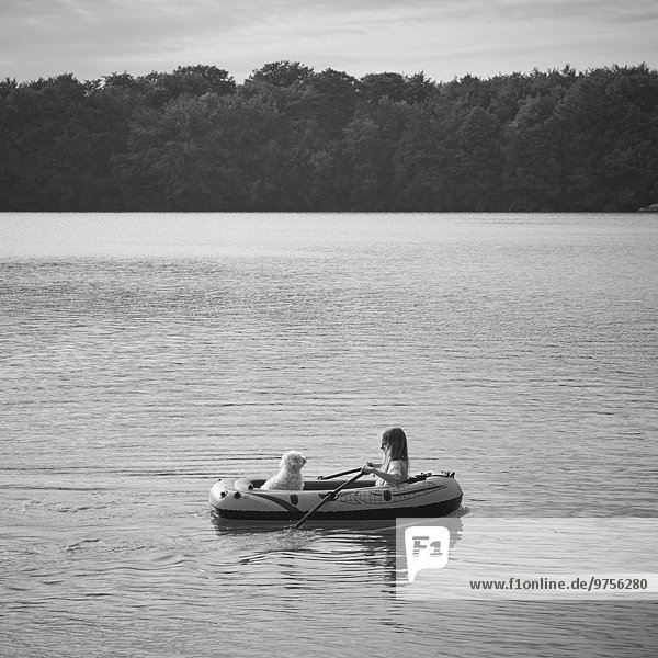Girl with dog in inflatable boat on lake