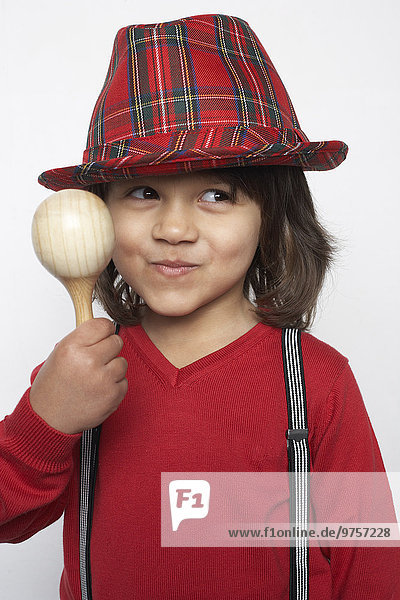 Porträt eines lächelnden kleinen Jungen mit hölzerner Rassel mit Hut und Hosenträgern