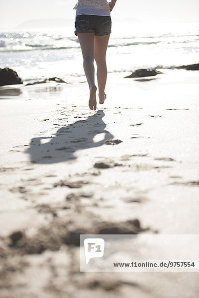 Legs of young woman running on beach