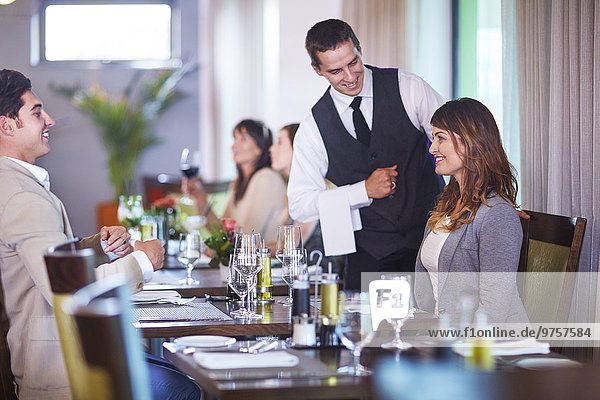Business people placing an order with waiter at hotel restaurant