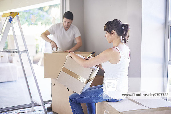Couple moving house  woman writing on box