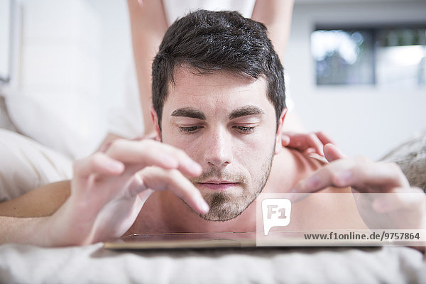 Mann im Bett liegend mit digitalem Tablett