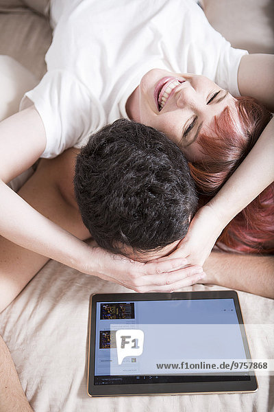 Junges Paar im Bett liegend mit digitalem Tablett