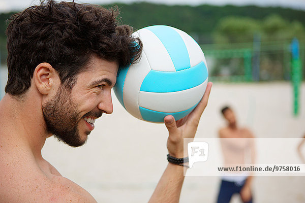 Lächelnder junger Mann hält Volleyball