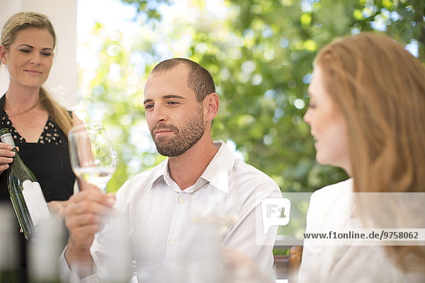 Mann bei der Untersuchung von Weißwein bei einer Weinprobe