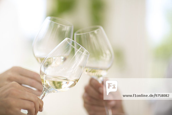 Hände halten Gläser mit Weißwein