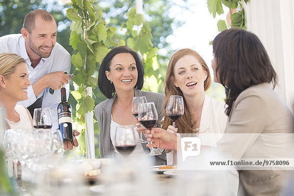 Waiter presenting bottle of red wine to women on a wine tasting session