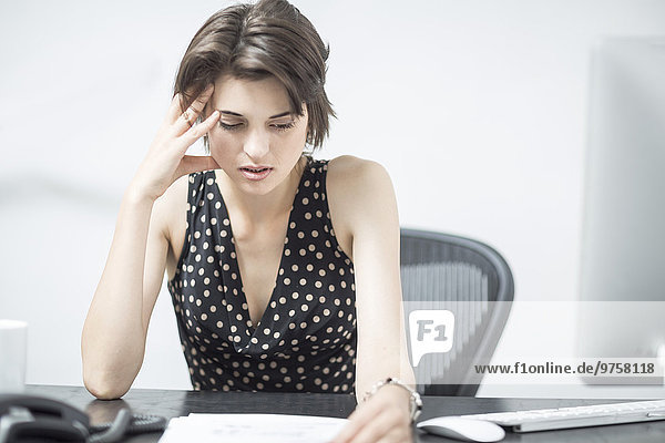 Frustrierte Geschäftsfrau am Schreibtisch sitzend