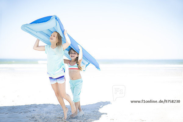 Zwei Mädchen am Strand mit einer Lilo