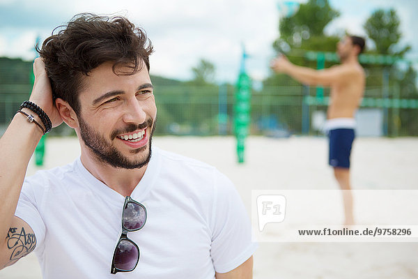 Smiling young man on beach volleyball field