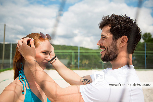 Junges Paar auf dem Beachvolleyballfeld