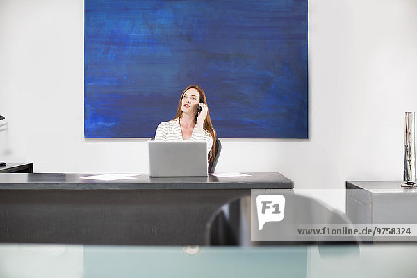 Geschäftsfrau im modernen Büro beim Telefonieren