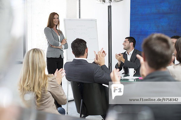 Businesswoman in boardroom leading a meeting with flip chart