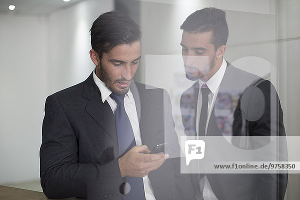 Two businessmen in office looking at cell phone