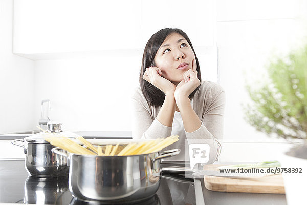 Porträt einer nachdenklichen jungen Frau beim Kochen von Spaghetti