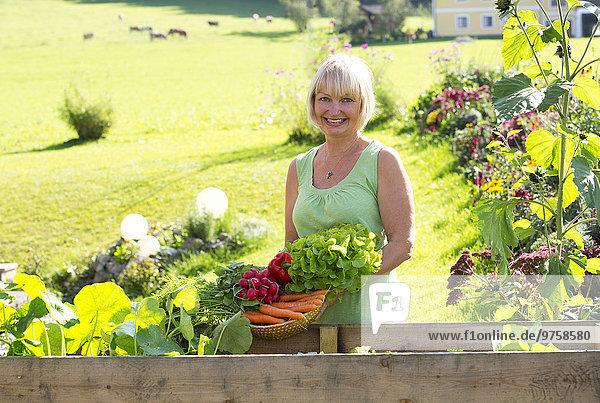 Österreich,  Mondsee,  Porträt der glücklichen Frau mit ihrer Gemüseernte