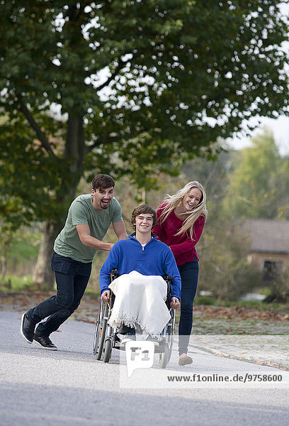 Young couple with friend sitting in wheelchair