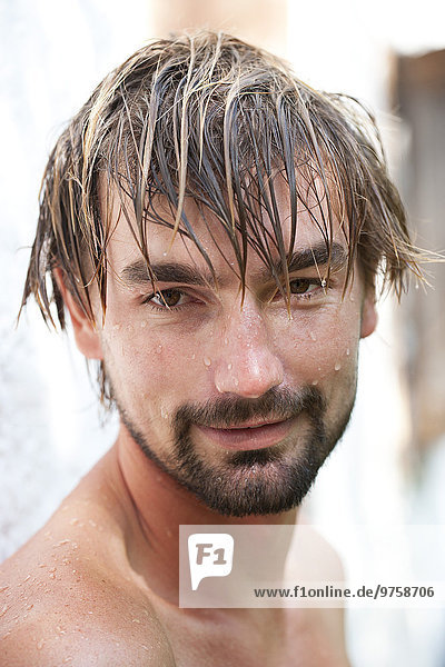 Porträt eines lächelnden Mannes mit nassem Gesicht und Haaren