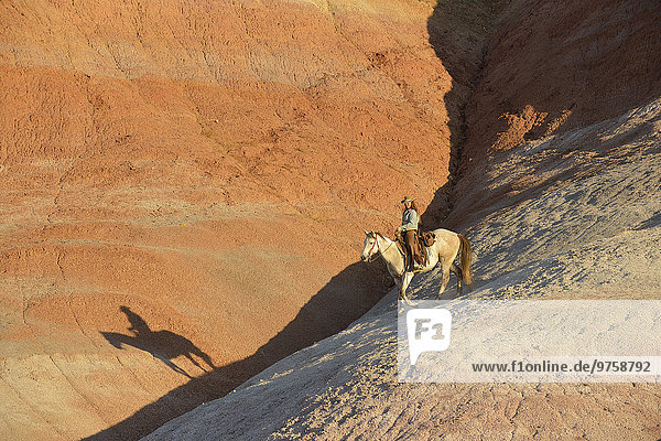 USA  Wyoming  cowgirl riding in badlands at twilight
