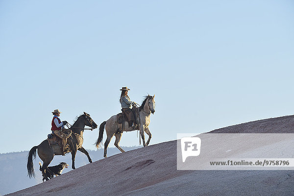 USA  Wyoming  zwei reitende Cowgirls und ihr Hund in Badlands