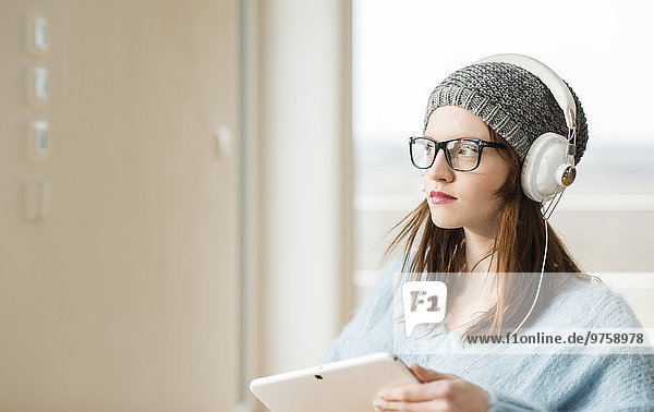 Junge Frau mit digitalem Tablett und Kopfhörer