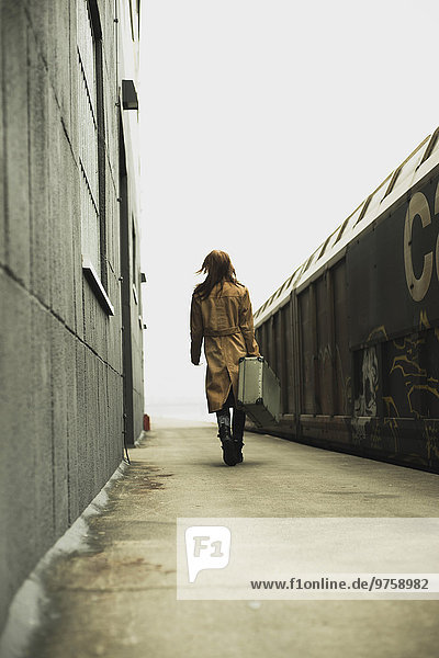 Junge Frau mit Koffer auf Plattform