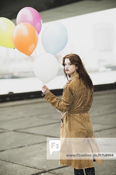 Junge Frau im Mantel mit Ballonstrauß