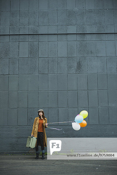 Junge Frau mit Koffer mit Ballonhülle