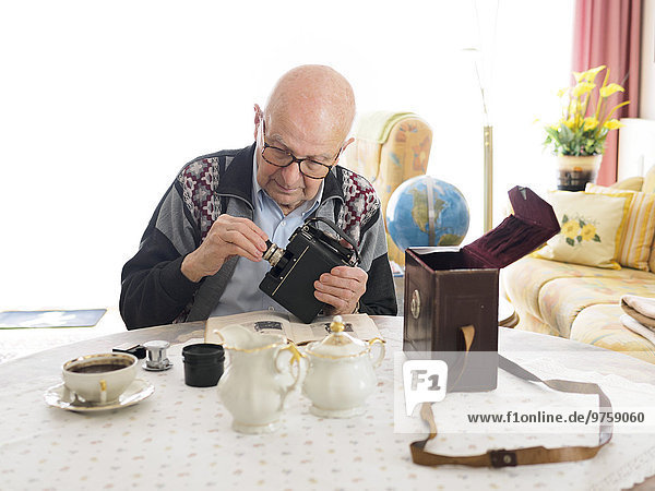 Alter Mann am Tisch sitzend mit alter Kamera