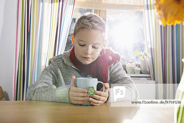 Junge mit einem kalten Sitzen in der Küche mit einer Tasse Tee