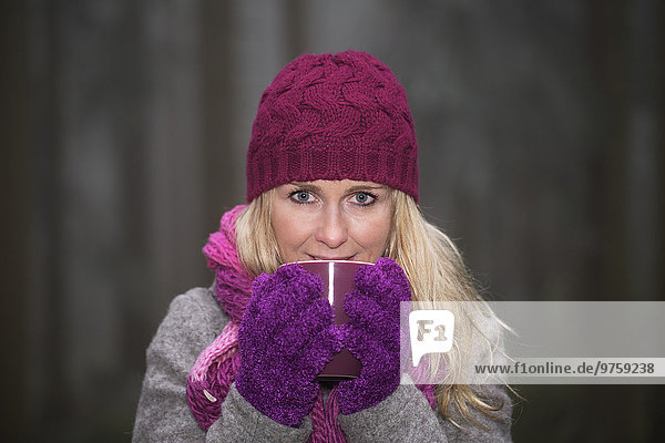 Österreich  Mittlere erwachsene Frau trinkt Tee im Winter  lächelnd