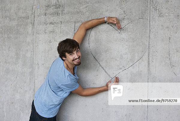 Mann umarmt Graffiti-Herz an der Betonwand