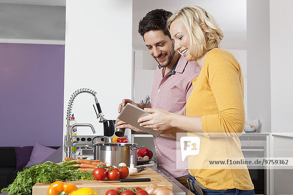 Couple cooking in kitchen using digital tablet