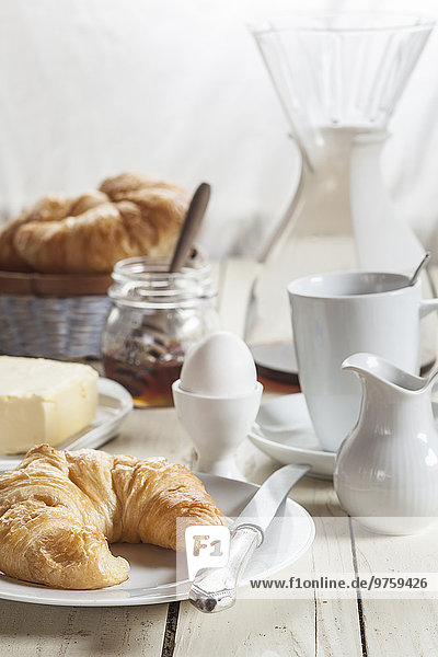 Frühstück mit Croissant,  Ei,  Kaffee,  Honig und Butter
