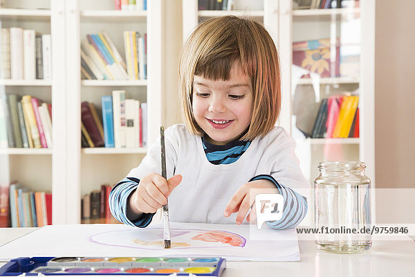 Portrait of smiling little girl painting with watercolours