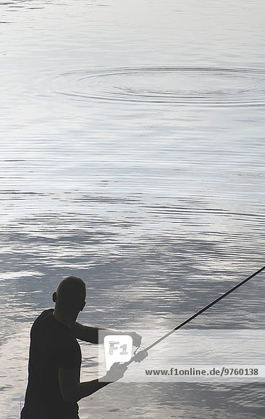 Silhouette des Mannes beim Fischen am Staudamm