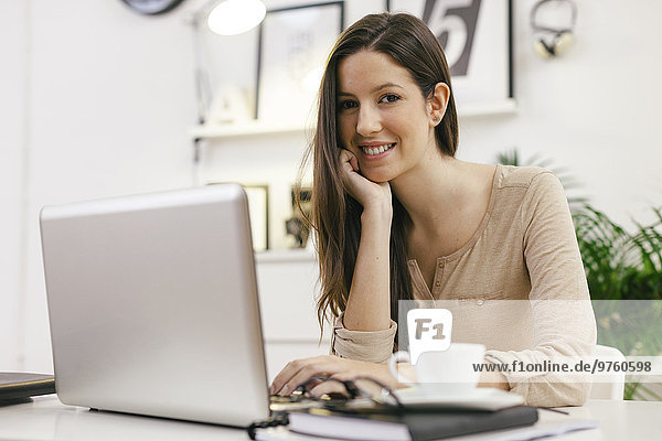 Young female entrepreneur with laptop at home office