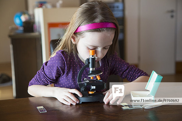 Kleines Mädchen mit Mikroskop zu Hause