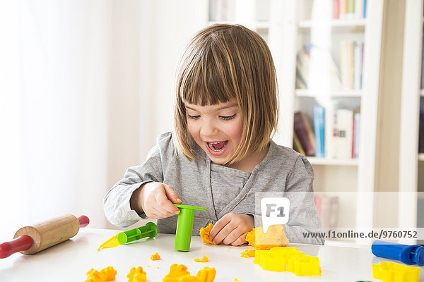 Little girl playing with yellow modeling clay