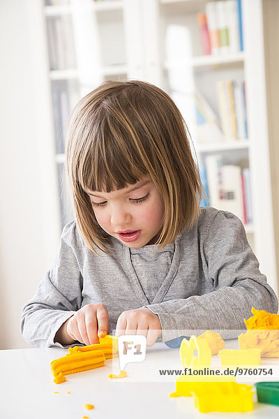 Little girl playing with yellow modeling clay