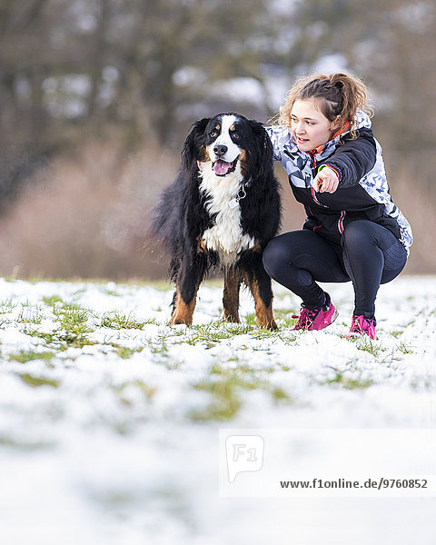 Germany  young woman with her Saint Bernard on snow-covered meadow