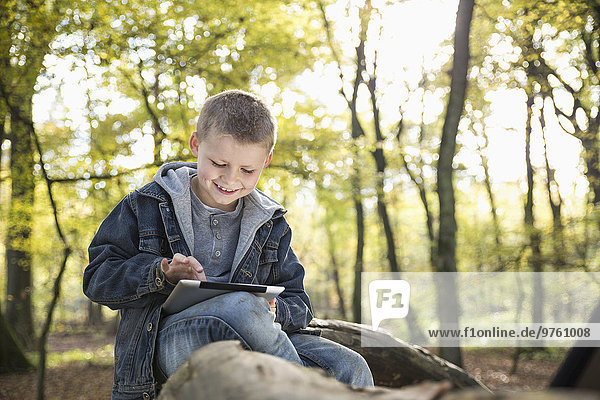 Deutschland  lächelnder kleiner Junge mit digitalem Tablett im Wald