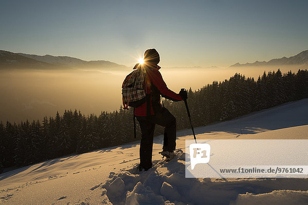 Österreich  Tirol  Schwaz  Frau Schneeschuhlaufen bei Sonnenuntergang