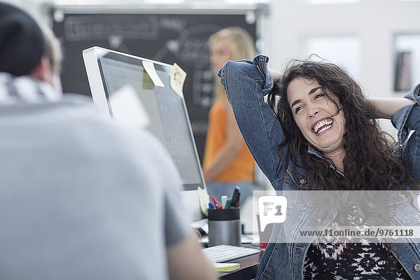 Glückliche kreative Bürofrau entspannt mit den Händen hinter dem Kopf