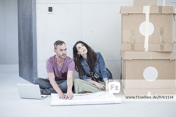 Kreative Büromenschen sitzen mit Bauplan und Boxen